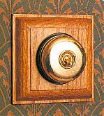 Arts & Crafts Movement style elegant brass single domed nipple electric light switch on square medium oak wooden backplate