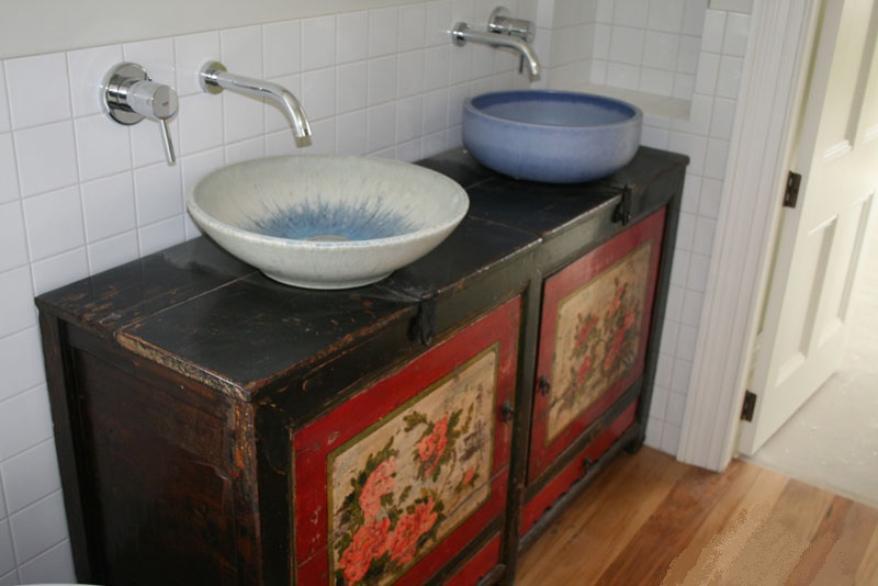Heavily antiqued folk art painted cupboard used as a vanity unit with sit on sink basins