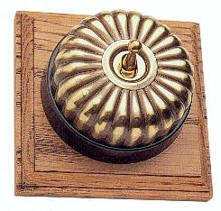 Arts & Crafts Movement style elegant fluted brass domed electric light switch on a square medium oak wooden backplate
